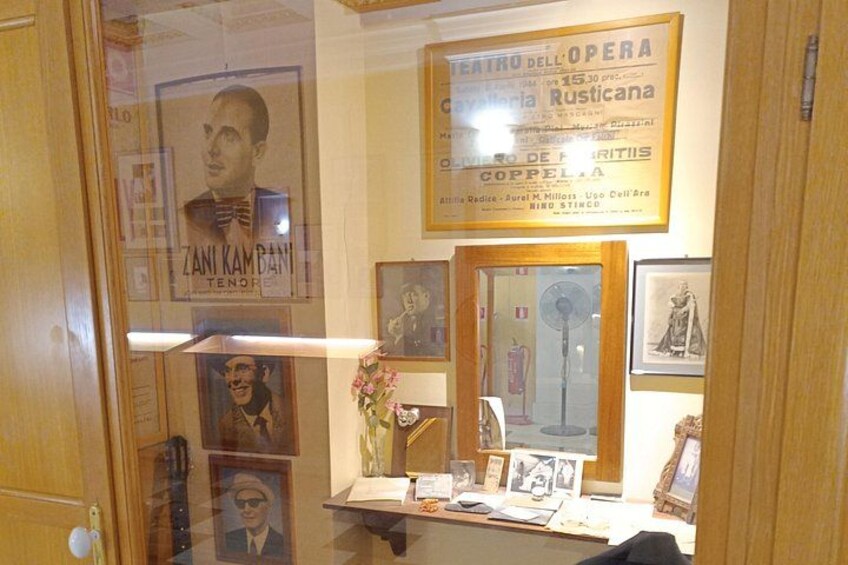 A room with framed posters, a mirror, and a small table with items. 5