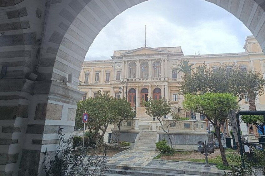 A classical building with columns, a courtyard with trees, and a stone archway. 4