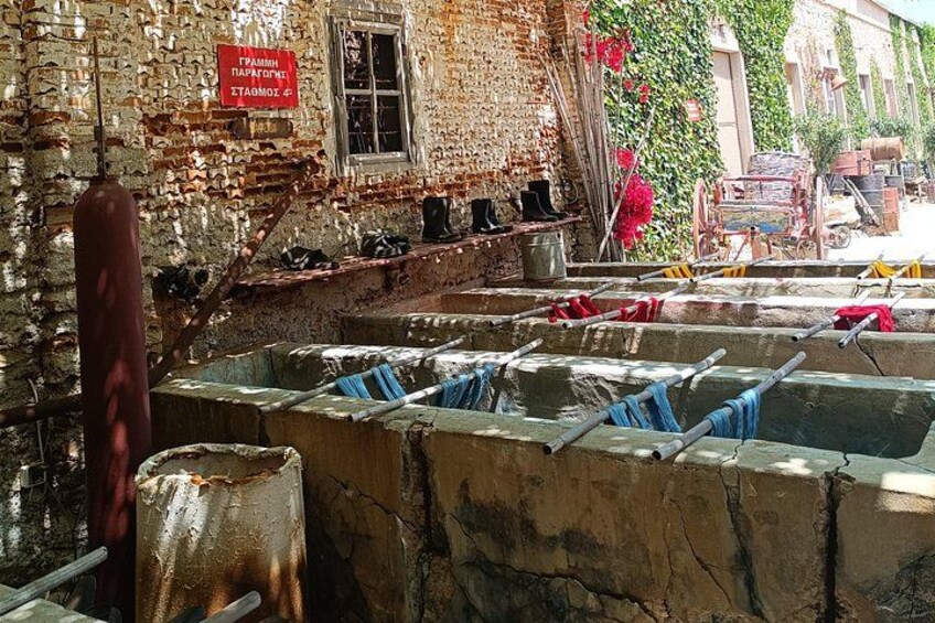 A rustic building with a brick exterior, a window, and a red sign. There are several concrete basins with blue cloths and metal rods. 3