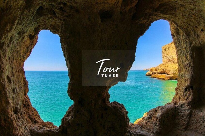 A rocky cave opening with a view of turquoise sea and a clear sky. 4