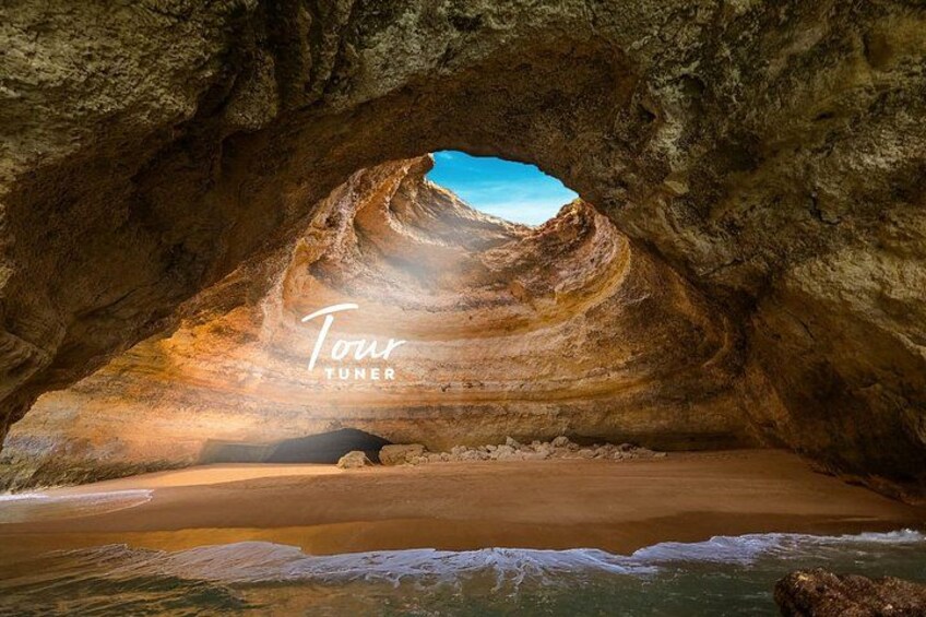 A cave opening to a beach with a clear sky. 2