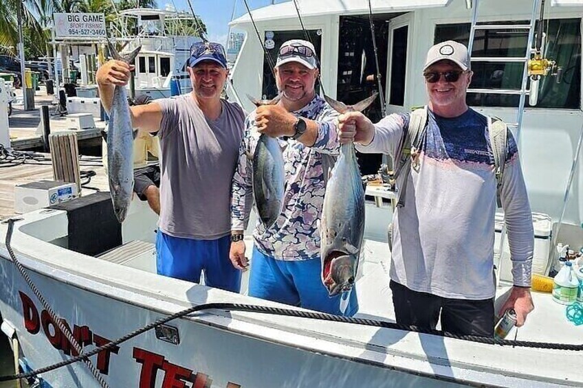Trois personnes se trouvent sur un bateau et tiennent des poissons. 3