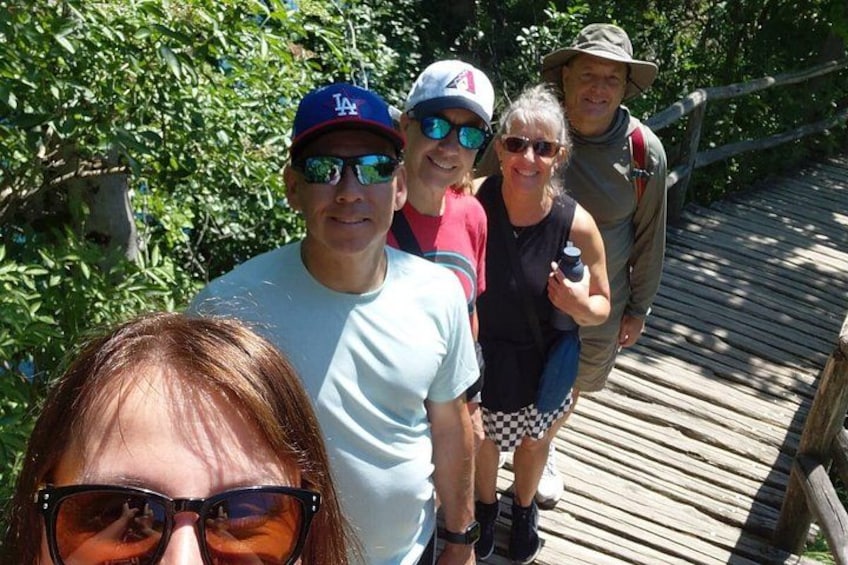 A group of people on a wooden bridge surrounded by greenery. 1