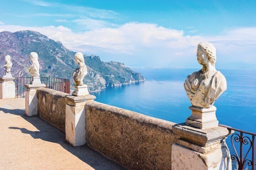 A coastal view with a stone balustrade and classical sculptures overlooking the sea. 3