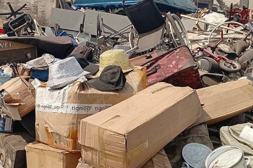 A pile of cardboard boxes and various discarded items, including bicycles and a bicycle helmet, in an outdoor setting. 5