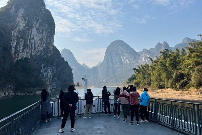 People standing on a bridge overlooking a river with cliffs. 5