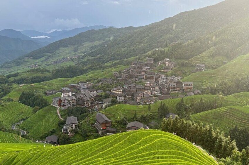 A village nestled in green hills with terraced fields and traditional buildings. 1