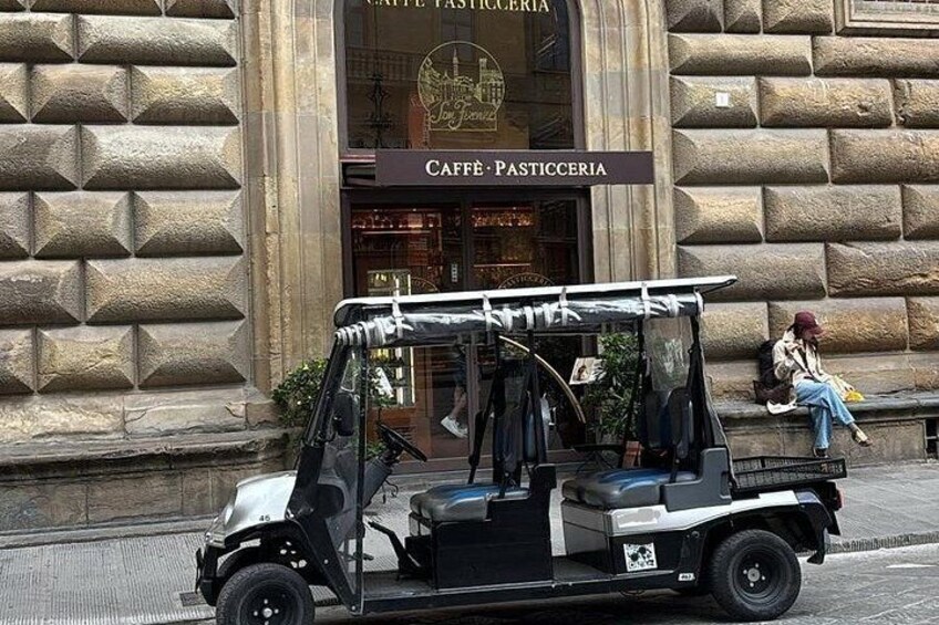 Un carrito de golf estacionado frente a un edificio con un letrero que dice 'CAFFÈ PASTICCERIA'. 2