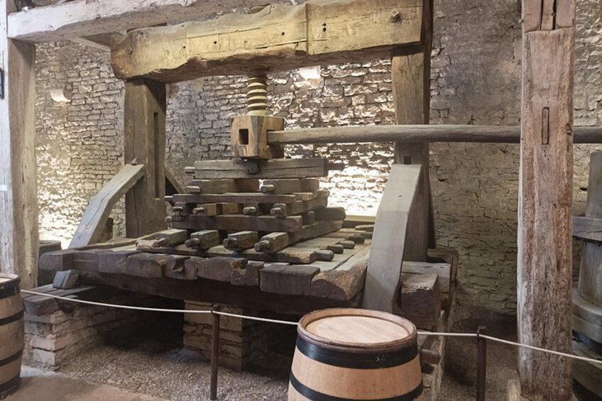 Una prensa antigua con componentes de madera y un fondo de pared de piedra. 5
