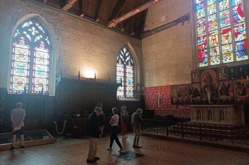 Interior de iglesia con vidrieras, bancos de madera y arte religioso en las paredes. 2