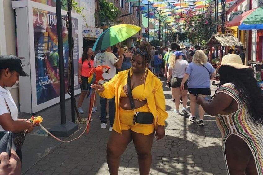 A crowded street with people walking, a woman in yellow, and colorful umbrellas. 3