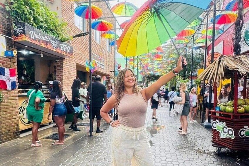 A street with people walking, umbrellas, and a food stall. 4