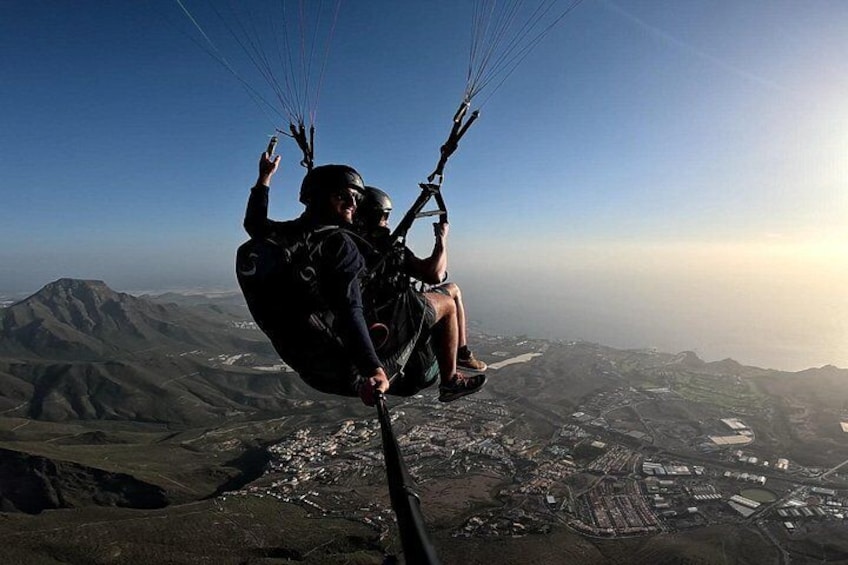 Una persona practica parapente sobre un paisaje montañoso con cielo despejado. 2
