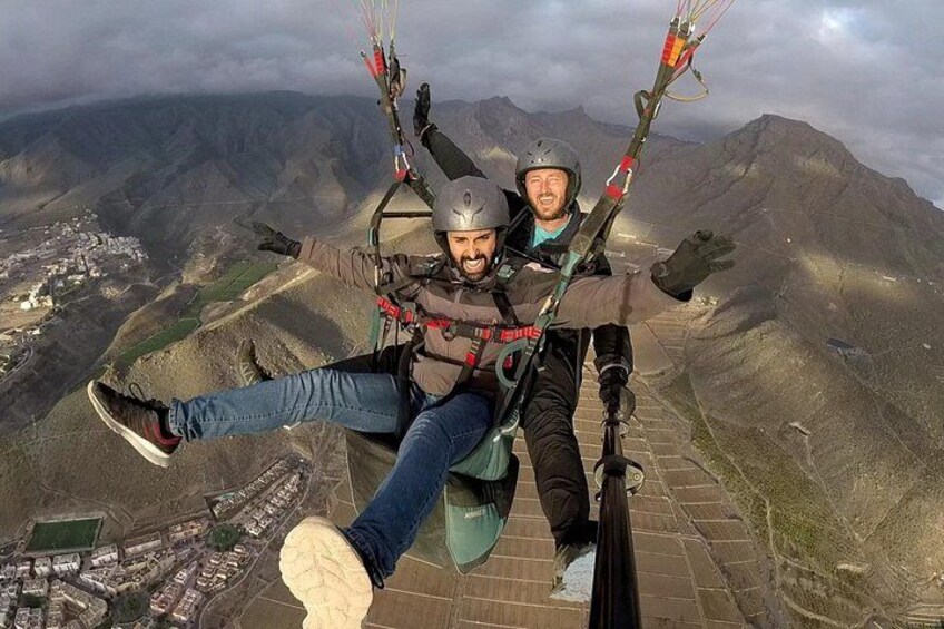 To personer paraglider med et bjergrigt landskab i baggrunden. 2