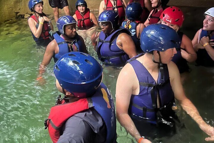A group of people wearing helmets and life vests in a body of water. 3