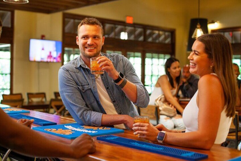 A person holding a drink at a bar with a television in the background. 3
