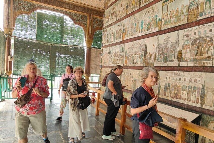 A group of people inside a building with ornate walls and benches. 5