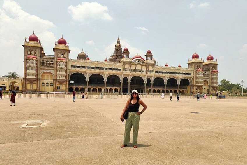 A large, ornate building with multiple domes and arches, a wide open plaza, and a few people in the foreground. 3