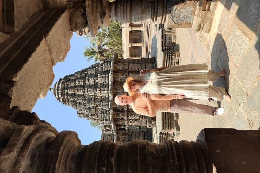 A person standing in front of a large stone structure with intricate carvings, possibly a temple or historical site. 2