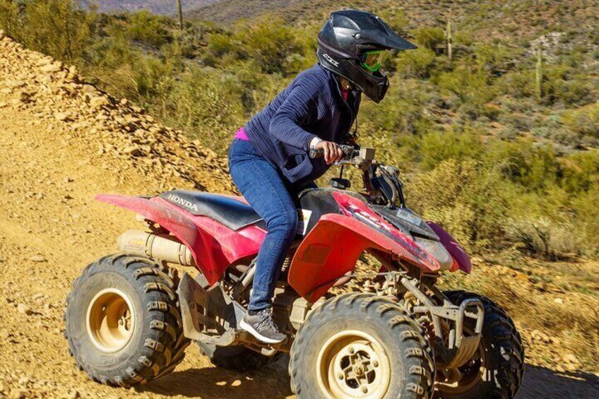 Una persona conduciendo un ATV Honda rojo por un sendero de tierra. 2