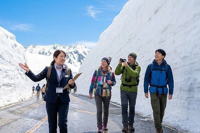 Un grupo de personas caminando por un sendero cubierto de nieve, con montañas al fondo. 1