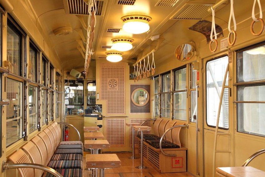 Interior de un tren antiguo con bancos de madera, barandales de metal y estantes para equipaje. 2