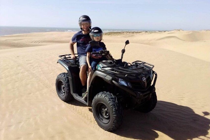 Twee personen op een quad rijden door een woestijn met zandduinen. 2