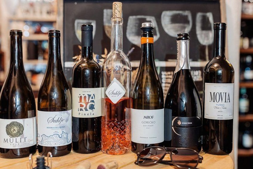 Une sélection de bouteilles de vin est présentée sur une surface en bois, avec un tableau noir en arrière-plan. 2