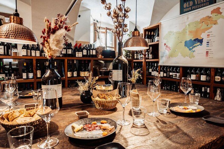Una sala per degustazioni di vino con un tavolo di legno, bicchieri da vino, bottiglie e una mappa appesa al muro. 2