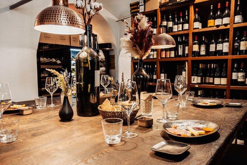 Une table en bois avec des verres à vin, des bouteilles et un plateau de fruits. 5