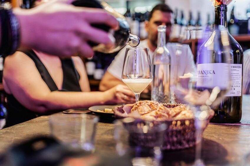 Une personne qui verse une boisson dans un verre, une bouteille de vin et un dessert sur une table. 3