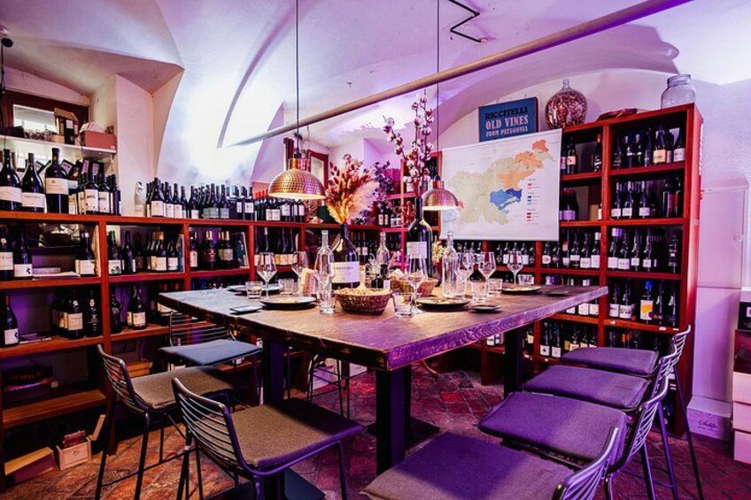 Une cave à vin avec des étagères remplies de bouteilles, une table avec des chaises et une carte accrochée au mur. 4