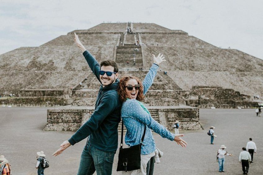 Un couple, les bras levés, se tient devant une grande structure en forme de pyramide. 1
