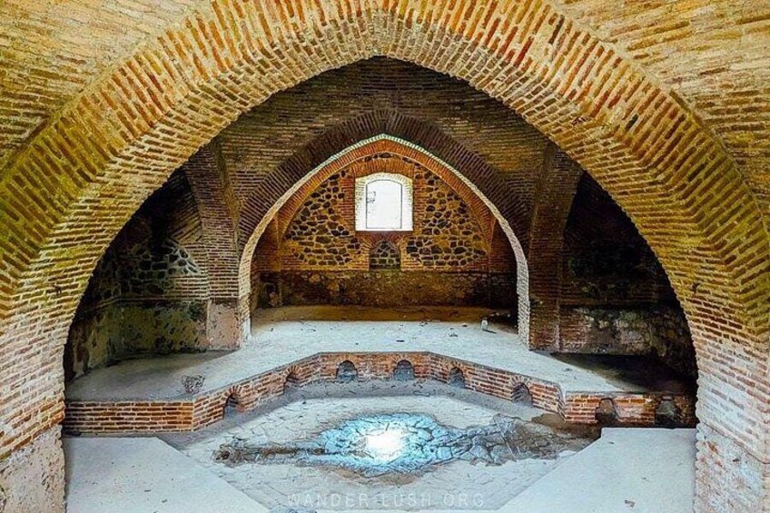 An arched brick structure with a central window and a circular stone feature. 2