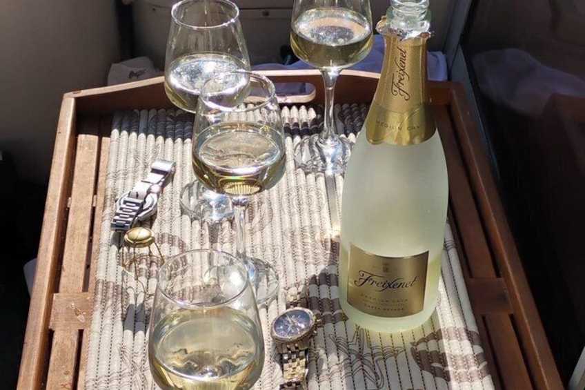 A tray with wine glasses, a bottle of Freixenet champagne, and a watch. 4