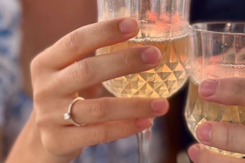 A person holding a glass with a diamond ring on their finger. 2