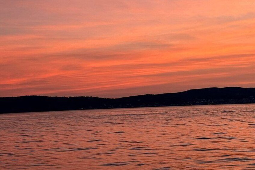 A sunset over a body of water with a silhouette of a landmass in the distance. 3
