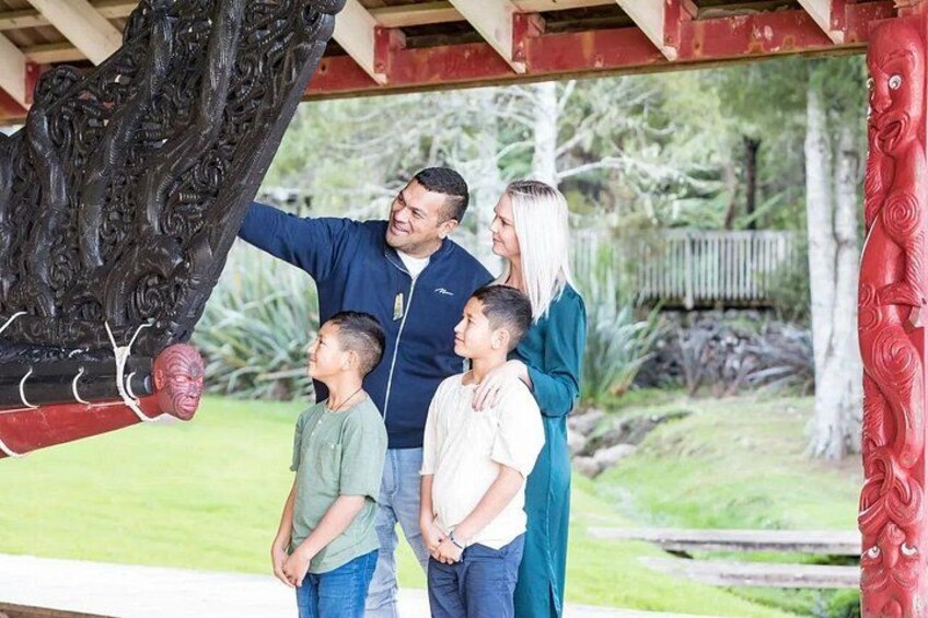 Una familia bajo una estructura de madera con intrincados grabados, un aro de baloncesto y un exuberante jardín verde. 2