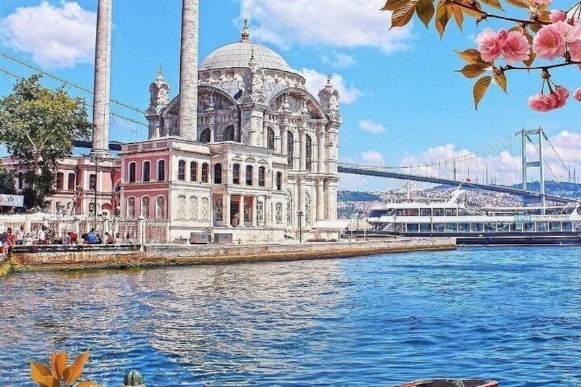 A historic building with a dome and columns by a river, with a bridge in the background. 2