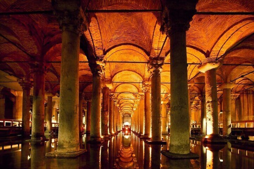 An interior with a long corridor flanked by columns and arches, reflecting light on the floor. 5