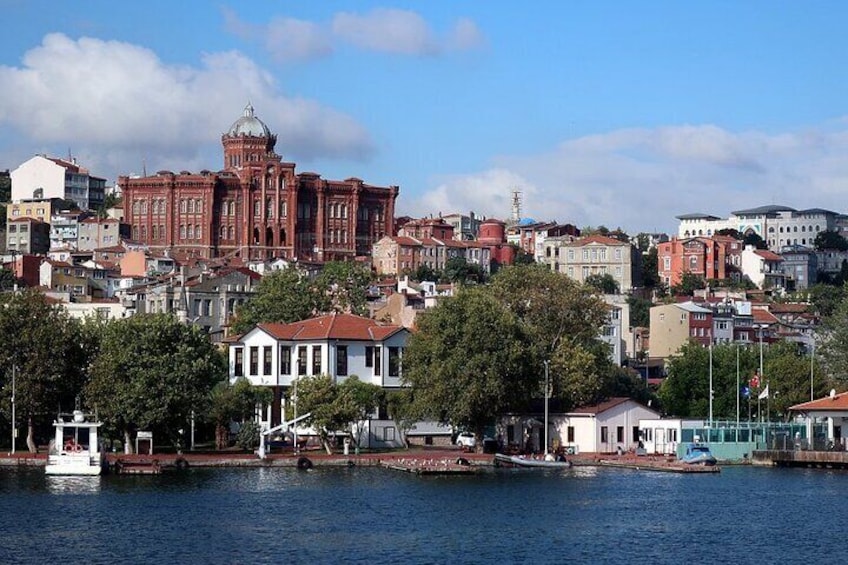 A waterfront cityscape with a prominent red-brick building, a white house, and a body of water. 4
