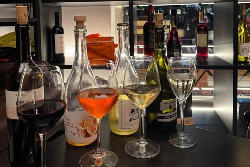 A bar with various bottles of wine and glasses on the counter. 1