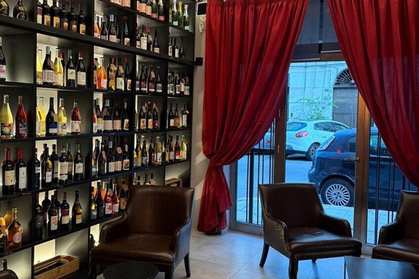 A bar with leather chairs, a wine rack, and red curtains. 3