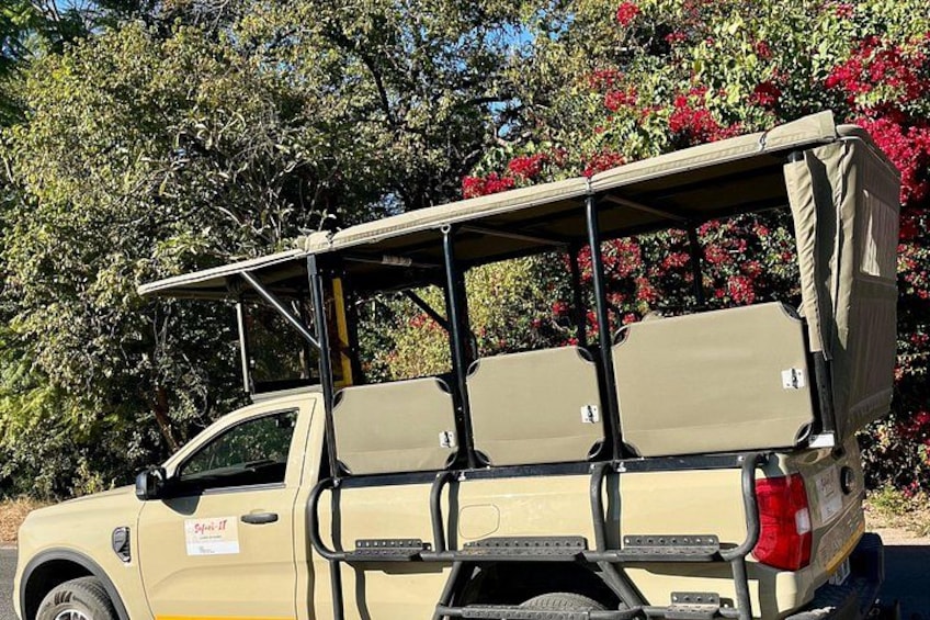A beige SUV with a roof rack and a spare tire mounted on the back. 1