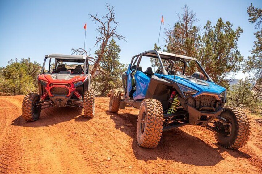 Two off-road vehicles on a dirt trail with sparse vegetation and a clear sky. 5