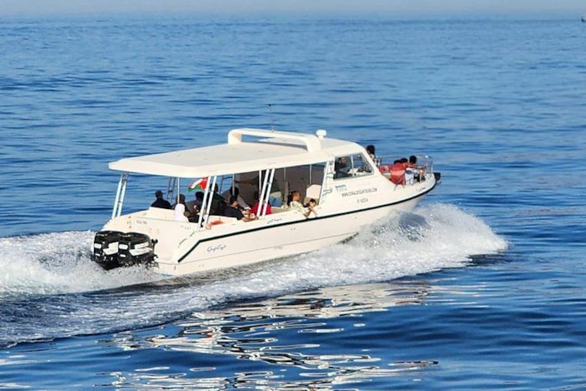 Una lancha blanca con pasajeros sobre un mar tranquilo. 3