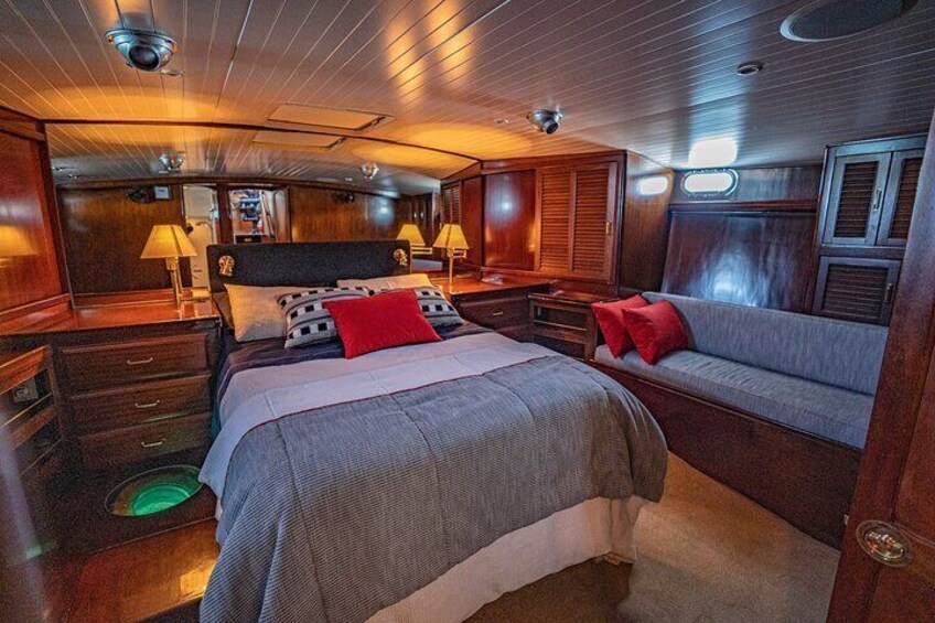 Un chalet confortable avec un lit, un canapé, des murs en bois et un plafond doté de luminaires. 4