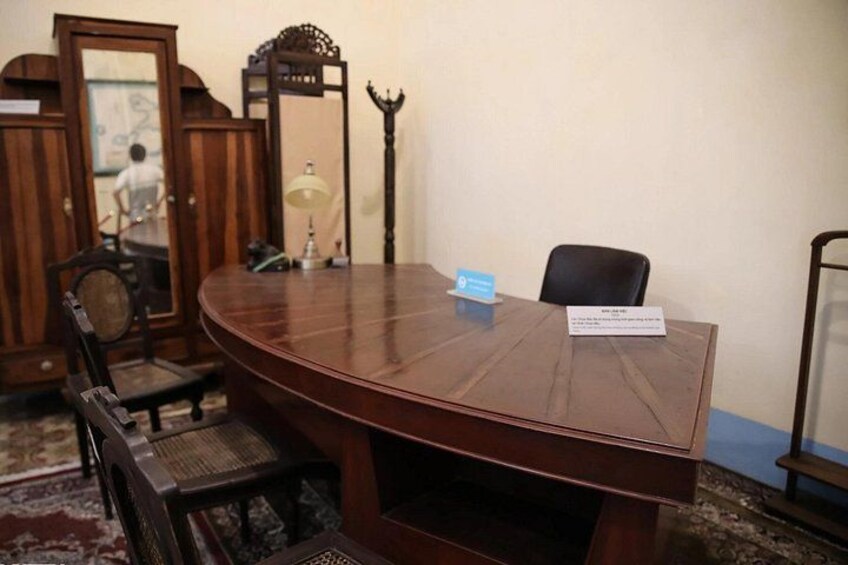 A conference room with a wooden table, chairs, a nameplate, and a mirror. 5