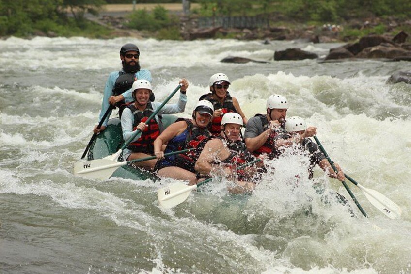 A group of people in a raft navigating through a river with rapids. 3