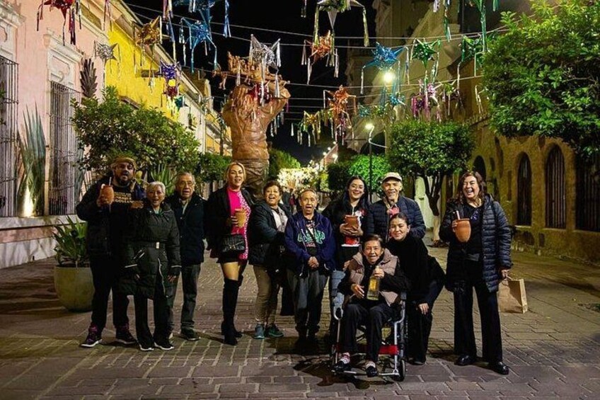 A group of people posing in an outdoor setting with a large sculpture and festive decorations. 2